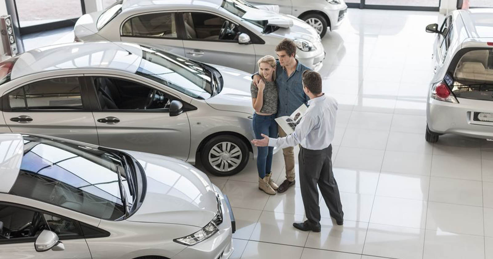 Salesperson showing a couple various cars on the showroom floor