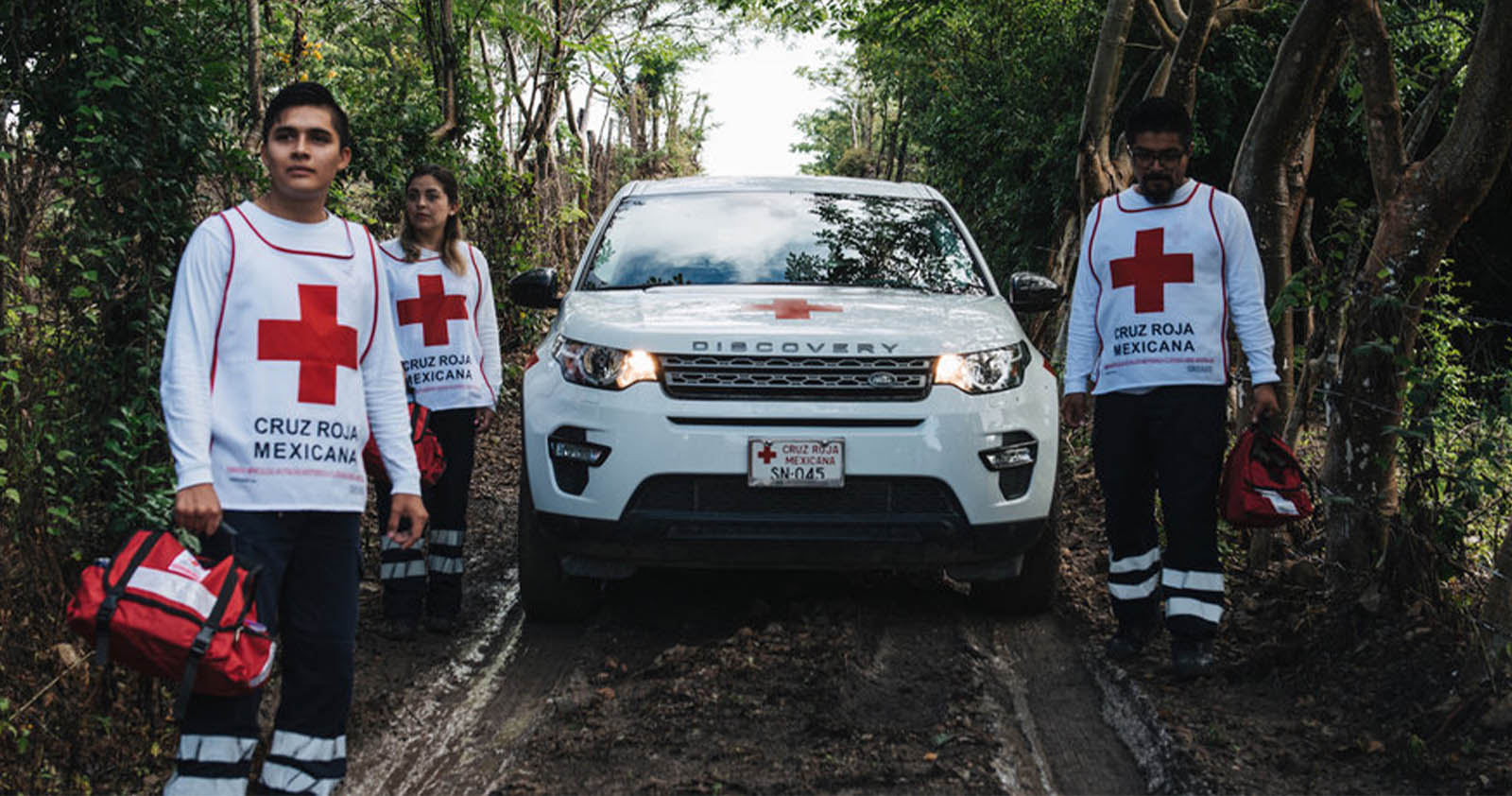 Red Cross workers next to White Land Rover Discovery