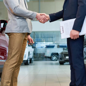 Two men shaking hands inside car dealership