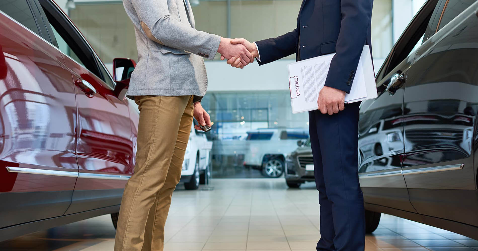 Two men shaking hands inside car dealership