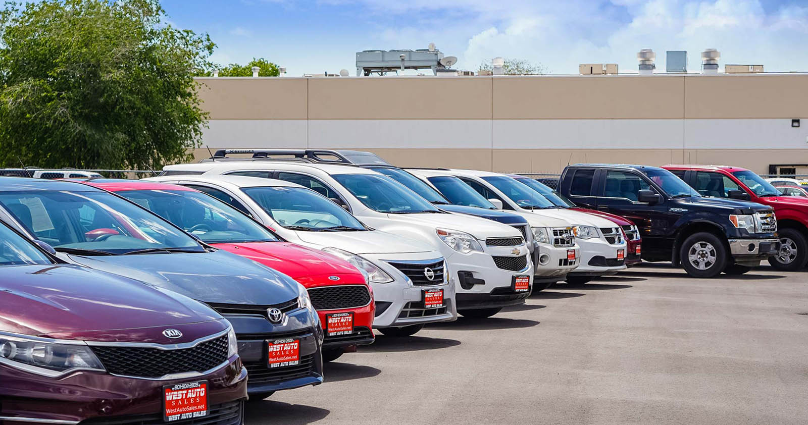 Various vehicles parked outdoors at a car dealership lot