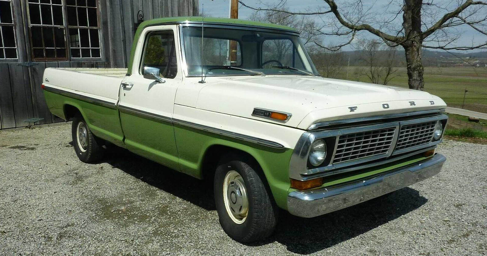 1970 white and green Ford F-100 pickup outside a barn