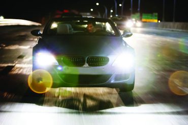 Man driving car on illuminated street at night
